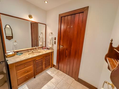 a bathroom with a sink and a wooden door at Mansão Nacional Inn in Campos do Jordão