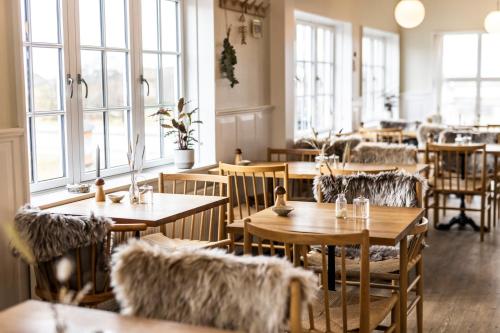 a restaurant with wooden tables and chairs and windows at Kellers Badehotel in Fanø
