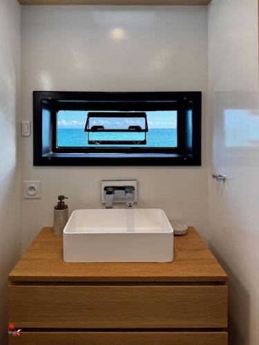 a bathroom with a white sink and a mirror at bateau in Les Trois-Îlets