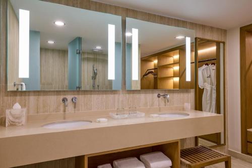 a bathroom with two sinks and a large mirror at Marriott Cancun, An All-Inclusive Resort in Cancún