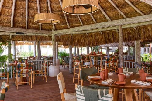 a restaurant with tables and chairs and a straw roof at Marriott Cancun, An All-Inclusive Resort in Cancún