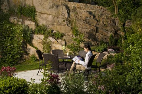 a man sitting at a table in a garden with a laptop at Landgasthof Zur schönen Wienerin in Marbach an der Donau