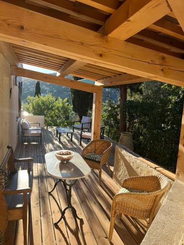 une terrasse en bois avec des chaises et une table dans l'établissement Maison Bord de mer Theoule, à Théoule-sur-Mer