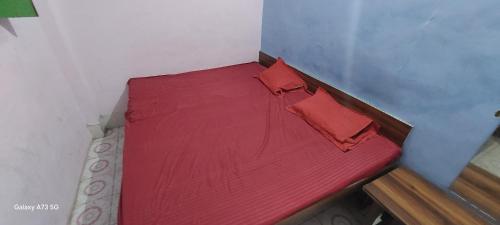 a small red bed with two red pillows on it at Hotel Vrindavan Near Vrindavan in Vrindāvan