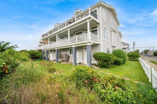 a large white house on a hill with bushes at Direct Ocean Front Townhouse! An oceanside gem perfect for any vacation! in Brigantine