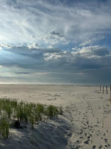 a beach with footprints in the sand and a cloudy sky at Direct Ocean Front Townhouse! An oceanside gem perfect for any vacation! in Brigantine