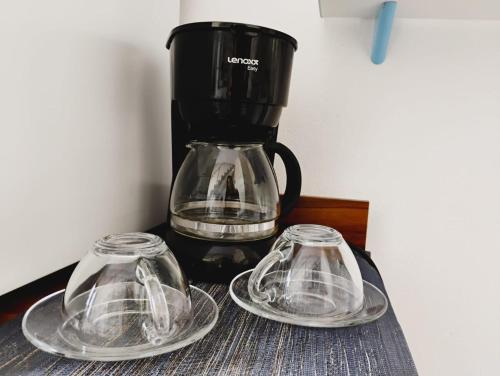 two glass plates and a coffee pot on a table at Apartamento Cavalcante in Belém