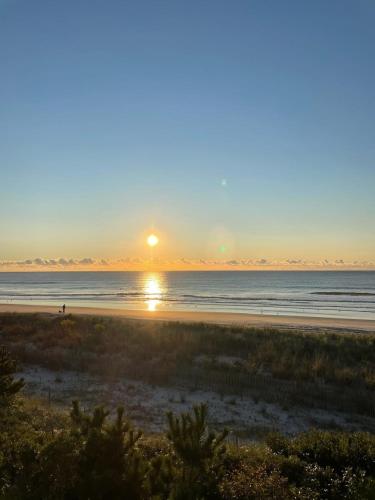 a beach with the sun setting over the ocean at Direct Ocean Front Townhouse! An oceanside gem perfect for any vacation! in Brigantine