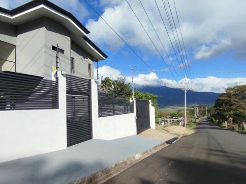 a white house with black shutters on a street at Casa con Piscina y jacuzzi, vista al Volcán Tenorio in Martirio