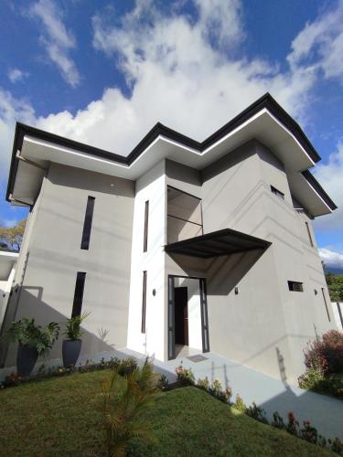 a white house with a black roof at Casa con Piscina y jacuzzi, vista al Volcán Tenorio in Martirio