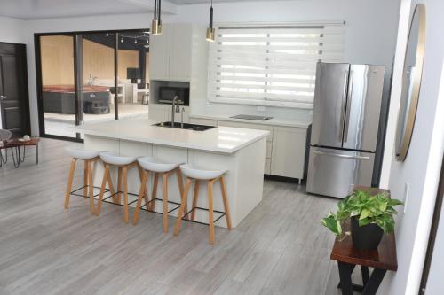 a kitchen with a white island and a refrigerator at Casa con Piscina y jacuzzi, vista al Volcán Tenorio in Martirio