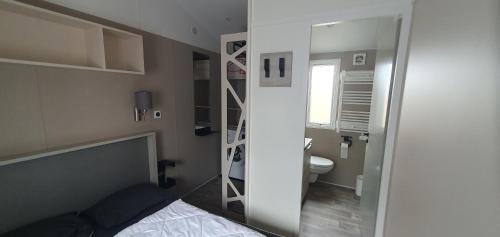 a room with a bed and a bathroom with a mirror at Mh 131 Bois Dormant fond d'impasse, 6 personnes in Saint-Jean-de-Monts