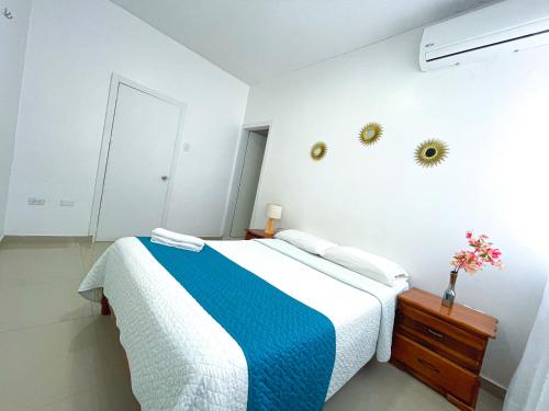 a white bedroom with a blue and white bed at HOSTAL PIAZZOLLA in Manta