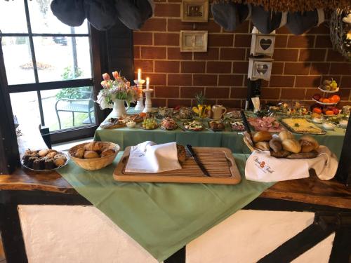 a table with a green table cloth with food on it at Landhaus Schlunt in Wustrow