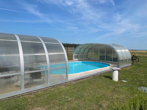 a greenhouse with a swimming pool in a yard at Landhaus Schlunt in Wustrow