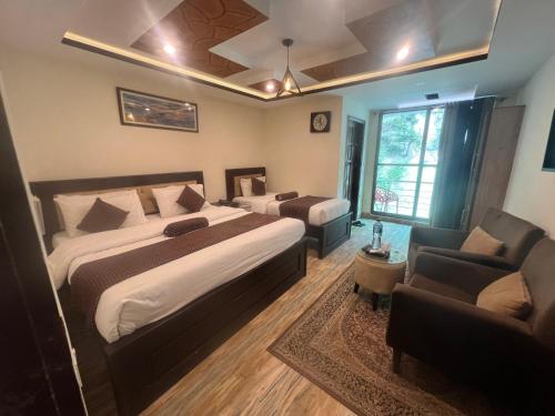 a bedroom with a bed and a couch and a chair at Hotel Birmingham Palace Kalam by Khan Familia Travels in Kalām