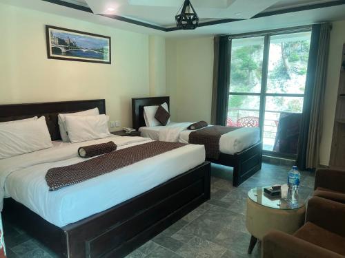 a hotel room with two beds and a window at Hotel Birmingham Palace Kalam by Khan Familia Travels in Kalām