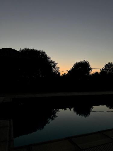 a sunset over a body of water with trees at Cheerful and cozy Bungalow with pool and fireplace in Athalassa
