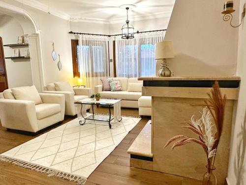 a living room with white furniture and a fireplace at Cheerful and cozy Bungalow with pool and fireplace in Athalassa