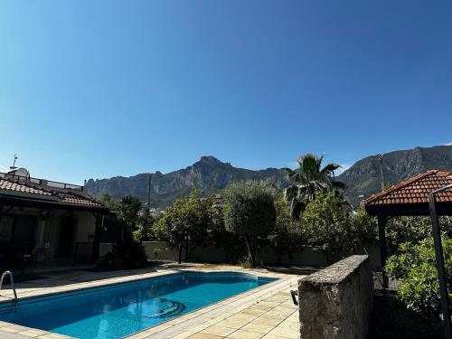 a swimming pool in front of a house with mountains at Cheerful and cozy Bungalow with pool and fireplace in Athalassa