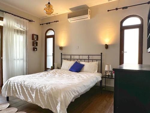 a bedroom with a bed with white sheets and blue pillows at Cheerful and cozy Bungalow with pool and fireplace in Athalassa