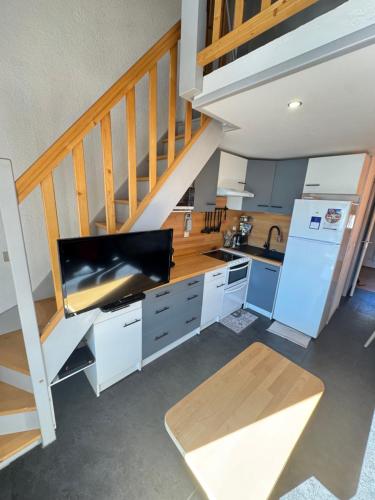 une cuisine avec des placards blancs et un escalier dans l'établissement L'Altitude Douce - Ski - Piscine - Tennis, à Gresse-en-Vercors