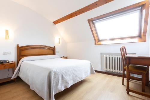 a bedroom with a bed and a desk and a window at Hotel Cabeza in Noreña