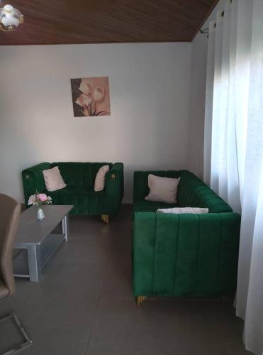 a living room with a green couch and a table at Résidesnce Merveilles M18 in Kribi