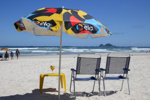 two chairs and a table under an umbrella on the beach at Delphin Beach Hotel in Guarujá