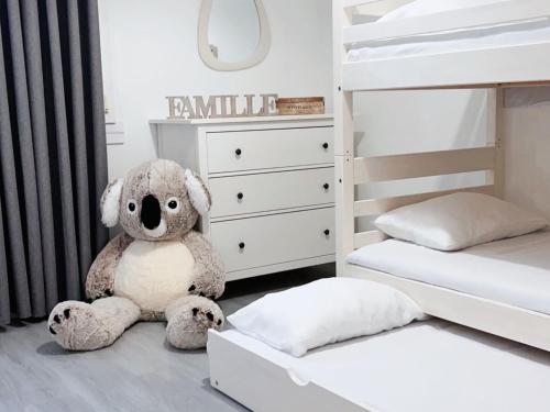 a large teddy bear sitting next to a bunk bed at Appartement 5 Lits, tout équipé, WiFi, NetfliX in Vaulx-en-Velin