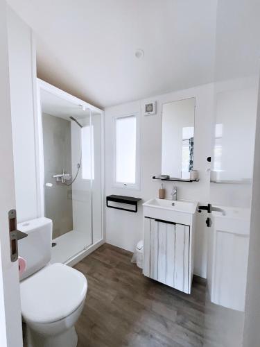 une salle de bain blanche avec des toilettes et un lavabo dans l'établissement Le Ti Buch Mobilhome en Camping 4 étoiles avec Terrasse Plancha et Climatisation, à La Teste-de-Buch
