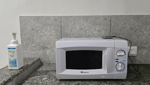 a microwave sitting on a counter next to a bottle of alcohol at Lyallpur Galleria Mall Apartment, 1 BHK, 1 Bedroom with Living Room, Basement Parking, 24x7 Security in Faisalabad