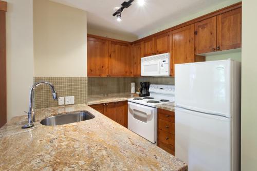 a kitchen with a white refrigerator and a sink at Lost Lake Lodge by Whistler Premier in Whistler