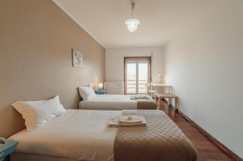 a hotel room with two beds and a window at Espinho Modern 3 Bedroom Apartment by Vacationy in Porto