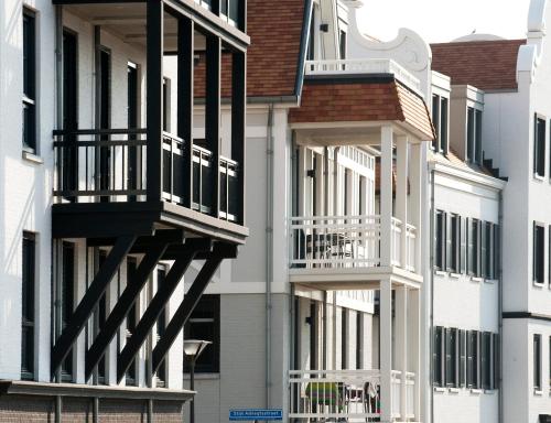 Une rangée d'appartements blancs avec balcon dans l'établissement Duinhof, à Cadzand-Bad