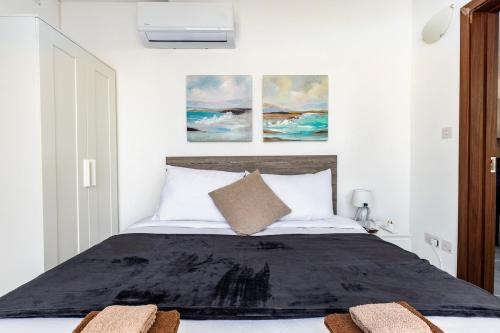 a bedroom with a bed with two paintings on the wall at Luigi penthouse in St. Paul's Bay