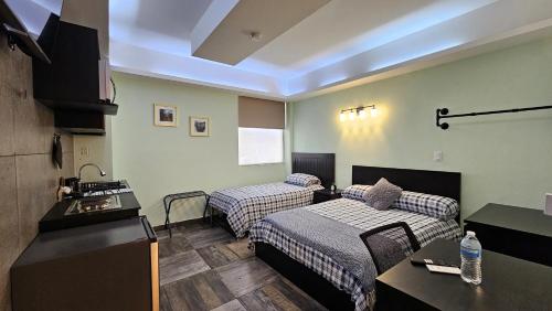 une chambre d'hôtel avec deux lits et une cuisine dans l'établissement A30 SUITE BLACK PLUS para 1 a 3 personas, ESPECIALISTAS EN CORTAS, MEDIANAS Y LARGAS ESTANCIAS , en IZCALLI TEPOTZOTLAN perfecto para Familias, Turistas, Contratistas, Estudiantes, Empresas A sólo 5 min Izcalli 5 min Esmeralda 20 min Satélite 25 min AIFA, à Cuautitlán Izcalli