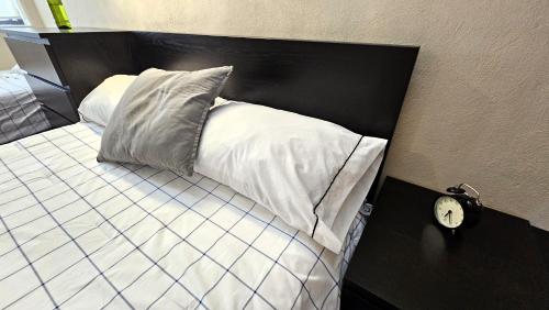 a bed with a black headboard and a clock on a table at A30 SUITE BLACK PLUS para 1 a 3 personas, ESPECIALISTAS EN CORTAS, MEDIANAS Y LARGAS ESTANCIAS , en IZCALLI TEPOTZOTLAN perfecto para Familias, Turistas, Contratistas, Estudiantes, Empresas A sólo 5 min Izcalli 5 min Esmeralda 20 min Satélite 25 min AIFA in Cuautitlán Izcalli