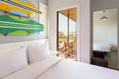 a bedroom with a bed and a view of a balcony at Radisson Blu Resort Taghazout Bay Surf Village in Taghazout