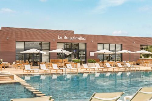 a swimming pool with chairs and umbrellas in front of a building at Radisson Blu Resort Taghazout Bay Surf Village in Taghazout