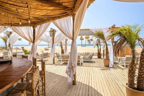 a resort patio with tables and chairs and the beach at Radisson Blu Resort Taghazout Bay Surf Village in Taghazout