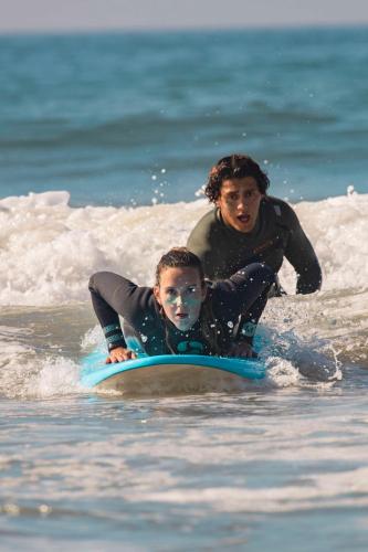 a woman and a child on a surfboard in the ocean at Radisson Blu Resort Taghazout Bay Surf Village in Taghazout