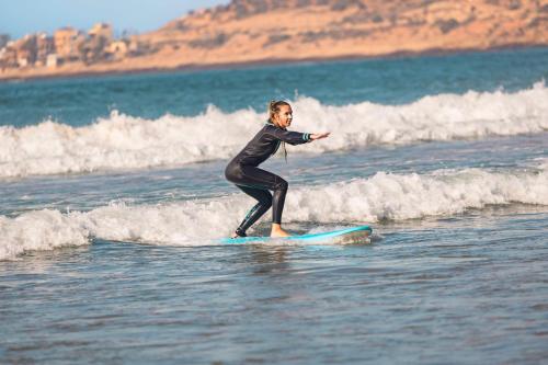 a woman riding a wave on a surfboard in the ocean at Radisson Blu Resort Taghazout Bay Surf Village in Taghazout