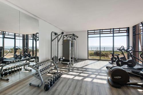 a gym with a lot of exercise equipment and windows at Radisson Blu Resort Taghazout Bay Surf Village in Taghazout