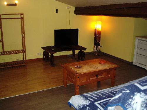 un salon avec un canapé et une table avec une télévision dans l'établissement hotellerie LE GRILLADOU, à Labastide-dʼAnjou