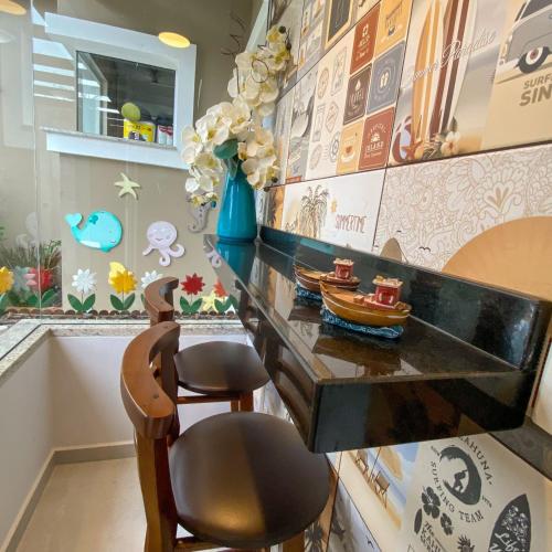 a desk with two chairs and a vase of flowers at Pousada Rota dos Mares in Penha