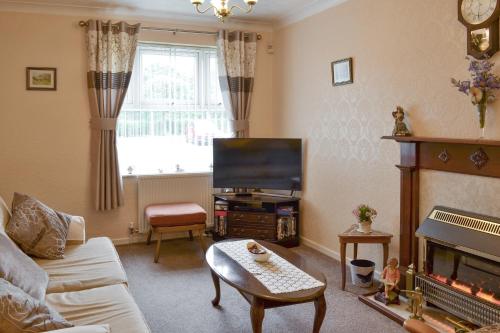 a living room with a couch and a tv at Cosy Corner in Bessingby