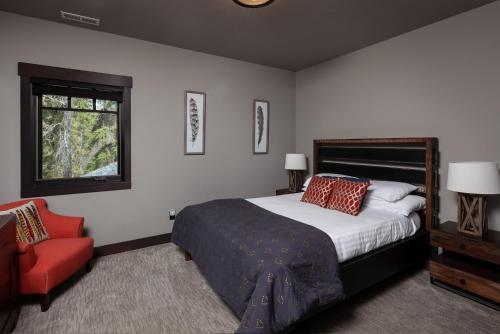 a bedroom with a bed and a red chair at Lodge at Whitefish Lake in Whitefish