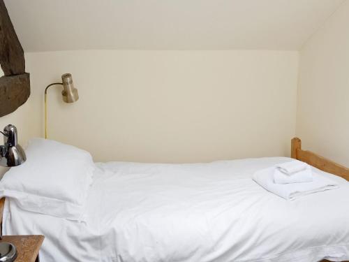 a bed with white sheets and a towel on it at The Coach House in Corney