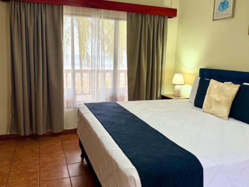 a bedroom with a large bed with a large window at Hotel Delfin Playa Bejuco in Esterillos Este